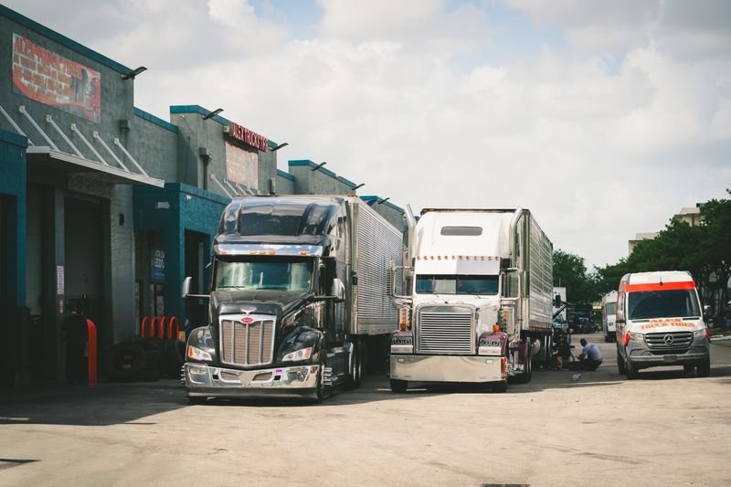 Tractocamiones Peterbilt y Freightliner frente al taller de Alex Truck Tire en Medley, junto a la van de servicio rotulada