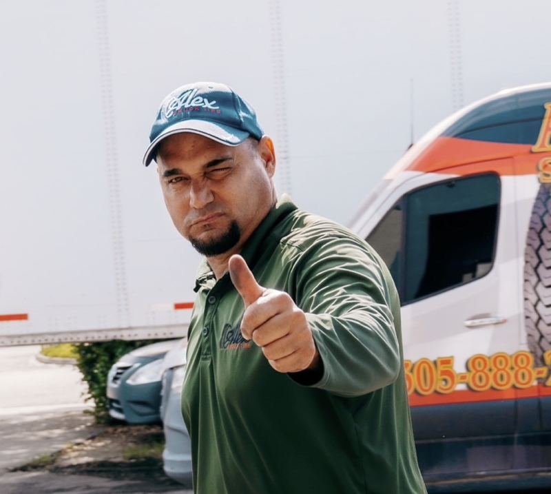 Alex Truck Tire team member giving a thumbs up next to a truck
