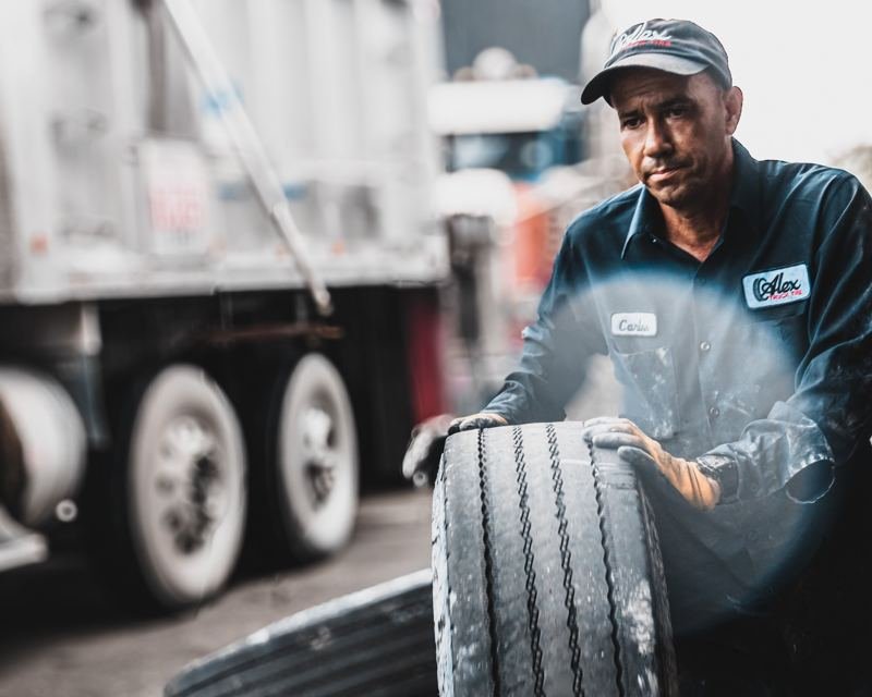 Técnico de Alex Truck Tire cargando un neumático en el taller